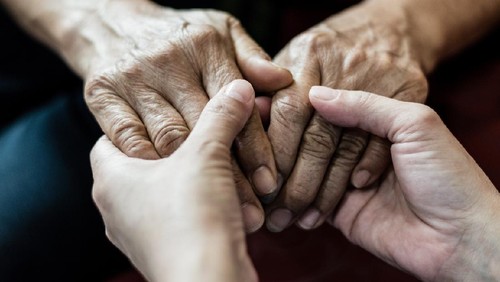 Parkinson and Alzheimer female senior elderly patient with caregiver in hospice care. Doctor hand with stethoscope check up older woman people. Old aging person seeing medical physician in hospital.