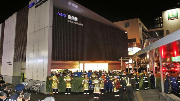 Emergency workers and police officers at a train station in Tokyo, Sunday Oct. 31, 2021 after a man brandishing a knife on a commuter train stabbed several passengers before starting a fire, which sent people scrambling to escape and jumping from windows, police and witness said. (Kyodo News via AP)