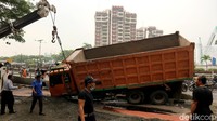 Alat berat dikerahkan untuk membantu proses evakuasi truk bermuatan pasir yang terguling di Jalan Gatot Subroto, Jakarta, Senin (1/11/2021).