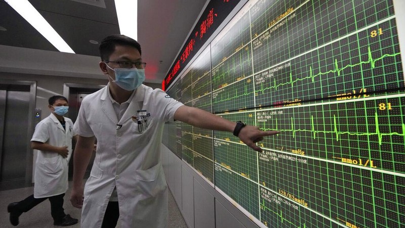 Chen Xiaofang, a nurse at the department of cardiovascular medicine the Guangdong Second Provincial General Hospital, stands next to a robot that delivers medicine in Guangzhou, in southern China's Guangdong province, Sunday, Sept. 26, 2021. The hospital in southern China's Guangdong Province is using 5G and IoT technologies to collect, transmit and monitor more data in real time, allowing healthcare workers to provide better medical service for patients. (AP Photo/Ng Han Guan)