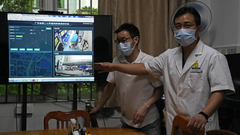 Chen Xiaofang, a nurse at the department of cardiovascular medicine the Guangdong Second Provincial General Hospital, stands next to a robot that delivers medicine in Guangzhou, in southern China's Guangdong province, Sunday, Sept. 26, 2021. The hospital in southern China's Guangdong Province is using 5G and IoT technologies to collect, transmit and monitor more data in real time, allowing healthcare workers to provide better medical service for patients. (AP Photo/Ng Han Guan)