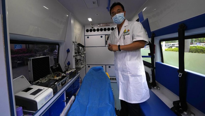 Chen Xiaofang, a nurse at the department of cardiovascular medicine the Guangdong Second Provincial General Hospital, stands next to a robot that delivers medicine in Guangzhou, in southern China's Guangdong province, Sunday, Sept. 26, 2021. The hospital in southern China's Guangdong Province is using 5G and IoT technologies to collect, transmit and monitor more data in real time, allowing healthcare workers to provide better medical service for patients. (AP Photo/Ng Han Guan)