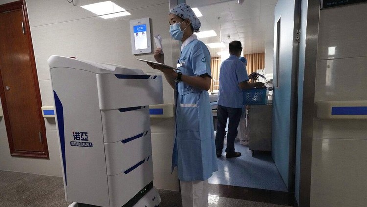 Chen Xiaofang, a nurse at the department of cardiovascular medicine the Guangdong Second Provincial General Hospital, stands next to a robot that delivers medicine in Guangzhou, in southern Chinas Guangdong province, Sunday, Sept. 26, 2021. The hospital in southern Chinas Guangdong Province is using 5G and IoT technologies to collect, transmit and monitor more data in real time, allowing healthcare workers to provide better medical service for patients. (AP Photo/Ng Han Guan)