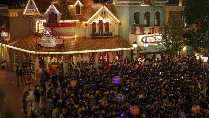 Disneyland employees gather to wait for their COVID-19 tests at the Shanghai Disney Resort in Shanghai, China on Sunday, Oct. 31, 2021. Fireworks boomed as the visitors at Shanghai Disneyland waited for their COVID-19 test results, surrounded by healthcare workers dressed from head to toe in the white protective suits. Shanghai Disneyland suddenly announced Sunday evening that they were no longer accepting any visitors and they were cooperating with an epidemiological investigation from another province. They then locked down the park, as Shanghai city healthcare workers and police rushed to the scene to conduct a mass testing. (Chinatopix via AP)