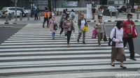 Sejumlah pekerja melintas di Jalan Sudirman, Jakarta, Selasa (2/11/2021).