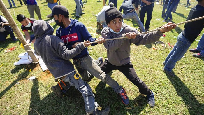 A man helps lift a giant kite to be displayed on All Saints Day as part of Day of the Dead celebrations in Santiago Sacatepequez, Guatemala, Monday, Nov. 1, 2021. For the second year the celebration has been reduced amid some restrictions to help curb the spread of the COVID-19. (AP Photo/Moises Castillo)