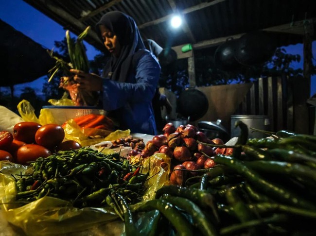 Pedagang sayur berdagang di bawah penerangan lampu listrik program listrik masuk desa daerah tertinggal di Dusun Jabal Antara, Aceh Utara.