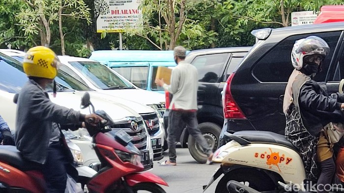 Pengemis membawa kardus meminta uang kepada pengendara di jalanan Makassar. (Hermawan/detikcom)