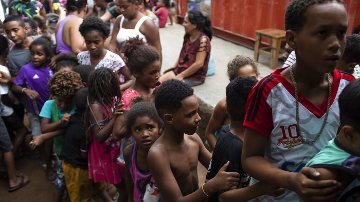 Perangi Kelaparan, 'Spiderman' Bagi-bagi Makanan di Brasil A volunteer dressed as Spiderman embraces a child in the Jardim Gramacho favela of Rio de Janeiro, Brazil, Saturday, Oct. 30, 2021, during a food kit delivery donated by the non-governmental organization