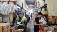Seorang pedagang menata dagangannya sambil menunggu pembeli di Pasar Benhil.
