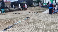 Ada juga warga yang bertahan usai menaruh sandalnya di antrean. Mereka menunggu antrean sambil duduk di kawasan Puskesmas.