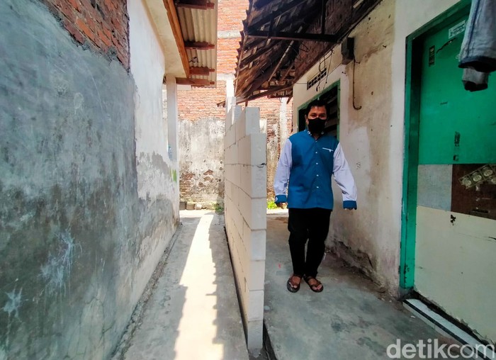 Tembok tetangga depan rumah keluarga Muhammad Ridwan (37) sudah dibongkar. Melalui jalan darurat itu, keluarga Ridwan dapat akses selebar 60 cm sampai satu meter. Ridwan merupakan Warga Rungkut Menanggal, Surabaya.