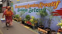 Warga melintas di lorong gang bergambar mural dengan tema budaya Betawi di kawasan Kampung Sentra Kreatif di RW 06 Kota Bambu Selatan, Palmerah, Jakarta Barat, Senin (1/11/2021).