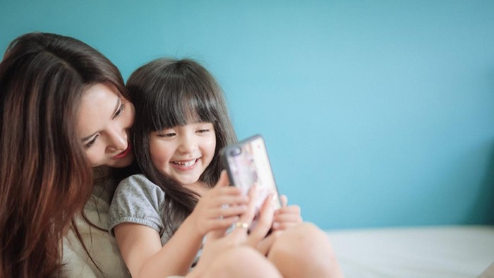 Portrait Happy Daughter playing smartphone with her mother