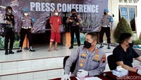 Meskipun diborgol, langkah kakinya tenang. Sesekali tampak mengernyitkan dahi sehingga kepala depannya yang mulai kehilangan rambut terlihat jelas.