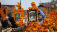 Penduduk setempat menggantung karangan bunga tradisional dari bunga marigold untuk menghiasi pintu masuk di pemakaman lokal. (Eduardo Ferdugo/AP)