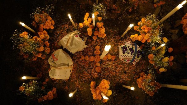 Penduduk menghiasi makam anak-anak dengan marigold dan lilin pada 31 Oktober, sementara untuk orang dewasa yang meninggal, perayaan dilakukan pada tanggal 1-2 November. (Eduardo Ferdugo/AP)