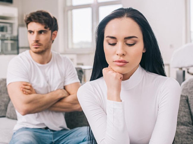 sad offended couple sitting on sofa after argument during self isolation at home