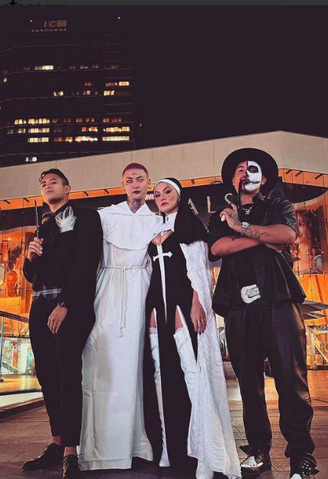 Sementara Adam Rosyadi, tampil ala Pendeta dengan mengenakan kostum panjang warna putih. Tampil dramatis, Adam pun mengenakan lipstik hitam dan lensa kontak putih. Agnez merayakan Halloween bersama sang kekasih di California, AS. Namun penampilan Agnez tersebut menuai kritikan karena dianggap terlalu seksi dengan mengenakan atribut keagamaan.Foto: dok. Instagram/@agnezmo