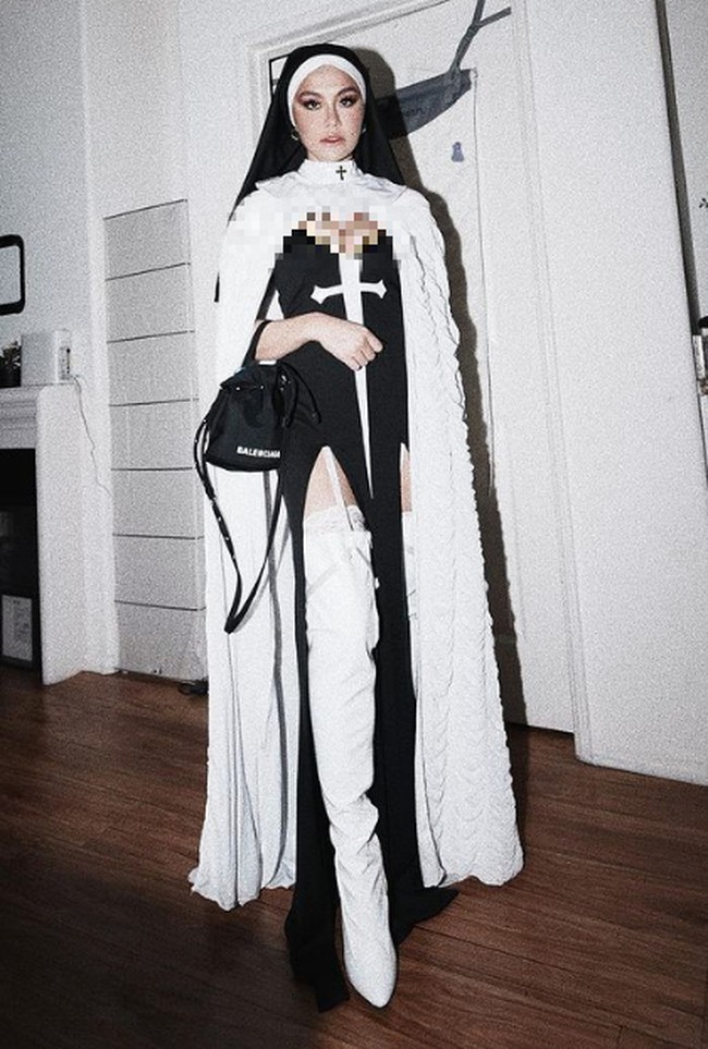 Agnez menggunakan pakaian biarawati yang telah dimodifikasi. Kostum tersebut memiliki unsur seksi dengan belahan-belahan di area tertentu. Dia pun memadankannya dengan kesan modern yakni menggunakan boots tinggi warna putih. Foto: dok. Instagram/@agnezmo