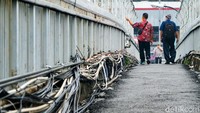 Warga melintasi Jembatan Penyeberangan Orang (JPO) di Jalan MT Haryono, Jakarta, Jumat (5/11/2021) sekitar pukul 10.30 WIB. Kabel-kabel semrawut tampak di sepanjang JPO.
