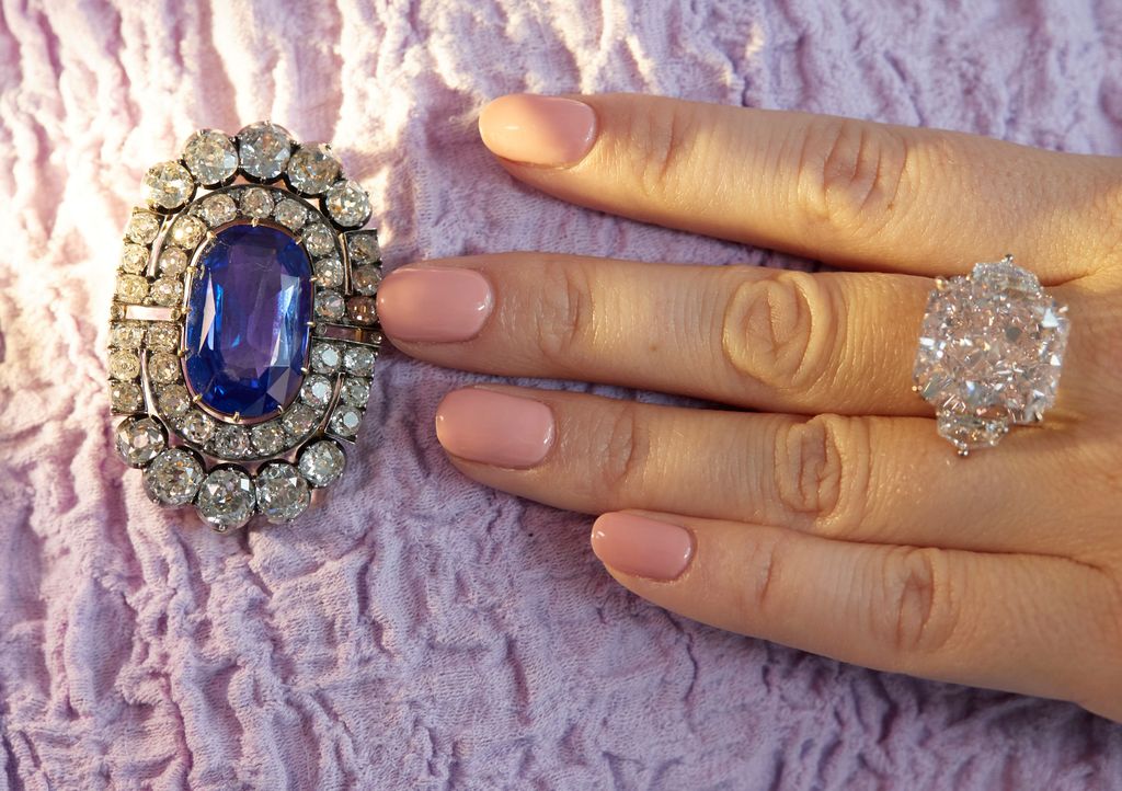 A staff holds member shows a historically valuable sapphire and diamond brooch and an orange-pink diamond ring weighing 25.62 carats during a preview at Sotheby's, before their auction sale in Geneva, Switzerland, November 2, 2021.  REUTERS/Denis Balibouse
