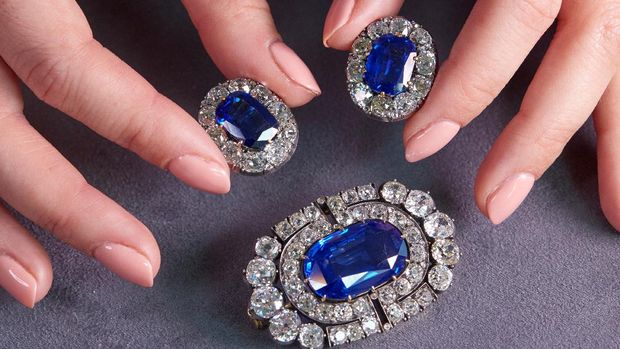 A staff member holds a historically valuable sapphire and diamond brooch and a pair of ear clips during a preview at Sotheby's, before their auction sale in Geneva, Switzerland, November 2, 2021.  REUTERS/Denis Balibouse