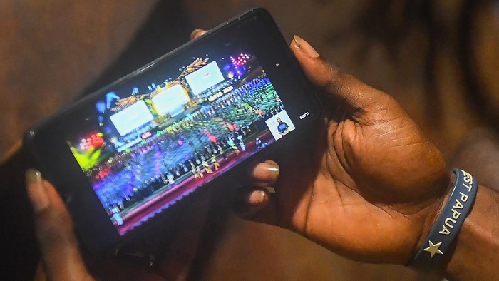 Warga menonton upacara pembukaan Peparnas Papua melalui gawainya di Toneowaa JR, Kota Jayapura, Papua, Jumat (5/11/2021). ANTARA FOTO/Rivan Awal Lingga/rwa.
