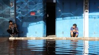 Sejumlah pekerja toko menunggu banjir rob surut.