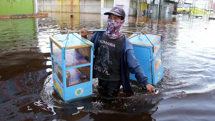 Sejumlah pekerja toko menunggu banjir rob surut di Dumai, Riau, Sabtu (6/11/2021). Banjir rob kembali menggenangi sebagian kota Dumai setelah sebelumnya dilanda banjir akibat hujan deras. ANTARA FOTO/Aswaddy Hamid/wsj.