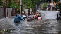 Berdasarkan foto yang dipotret sekitar pukul 17.03 WIB, tampak sejumlah warga melintasi banjir di kawasan Pela Mampang, Jakarta, Minggu (7/11/2021).
