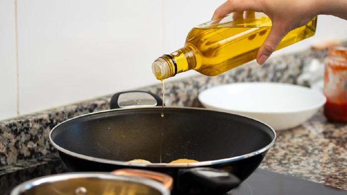 Cooking meal in a pot. Bottle of Extra virgin oil pouring in to pot for cooking meal. Healthy food concept.