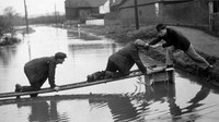 Tak kalah unik, dalam foto yang dipotret sekitar tahun 1935, tampak sejumlah warga memanfaatkan tangga kayu dan sebuah keranjang untuk dijadikan jembatan darurat agar tubuhnya tak basah terendam banjir. Topical Press Agency/Getty Images.