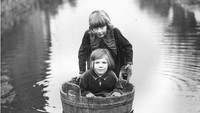 Seorang anak duduk di dalam bak mandi kayu saat banjir merendam kawasan Langport, Somerset, pada bulan Desember 1935. Fox Photos/Getty Images