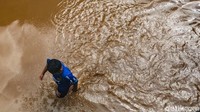 Seorang anak kecil berjalan melewati banjir.