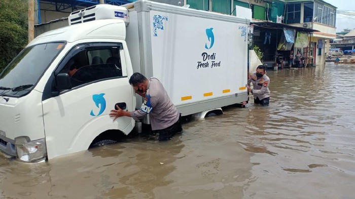 Polisi bantu dorong mobil yang mogok akibat banjir rob di kawasan Pelabuhan Muara Baru, Jakut