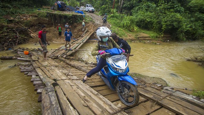 Potret Perjuangan Warga Lintasi Jembatan Darurat di Kalsel Jembatan utama Desa Murung B, Hantakan, Kalimantan Selatan, ambruk terbawa arus luapan sungai. Kini warga terpaksa menyeberang melewati jembatan darurat yang licin.