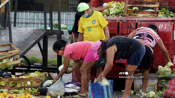 People collect fruits and vegetables discarded by street vendors in Belem, Para state on November 4, 2021. - According to the Brazilian government, approximately 19 million people in Brazil have gone hungry over the past year, almost twice the 10 million who did so in 2018. Approximately 55 percent of the country's population is now facing food insecurity, and at least 15 percent lives with a daily and constant lack of food. Once considered an upper middle income country, Brazil had been removed in 2014 from the World Food Programme's Hunger Map after a decade of progress in reducing hunger. (Photo by Raimundo Pacco / AFP)