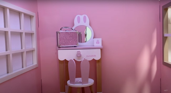 Sedangkan untuk rumah-rumahan yang terletak di bagian atas, bagian dalamnya tampak didominasi warna merah muda. Terdapat sebuah tas makeup kecil dengan glitter berwarna merah muda, serta bangku dan meja rias berwarna senada. Foto: YouTube/NisNaz Channel