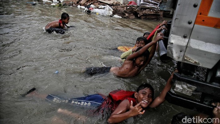 Sejumlah anak-anak pesisir di kawasan Muara Angke, Jakarta Utara, tampak semringah saat bermain di tengah banjir rob.