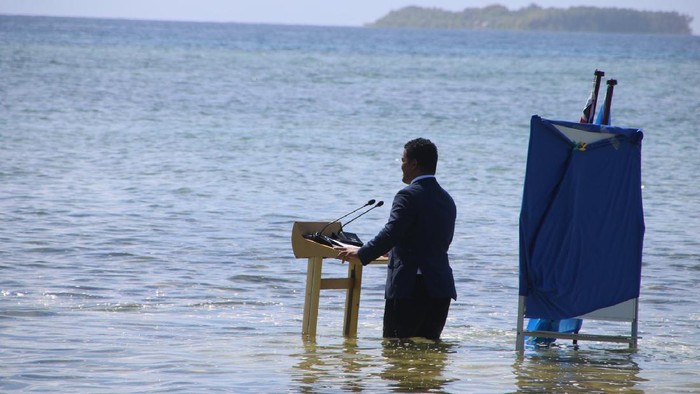 Menlu Tuvalu Simon Kofe Menteri Luar Negeri Tuvalu, Simon Kofe, memberikan pidato untuk Konferensi Perubahan Iklim (COP26) di pantai laut. Kofe berdiri menceburkan diri dengan lutut terendam air laut, sembari ditemani bendera Perserikatan Bangsa-Bangsa (PBB) dan bendera kebangsaan negara itu.