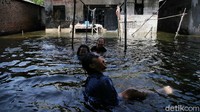 Anak-anak bermain di genangan banjir.