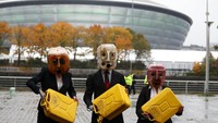 Aktivis berunjukrasa mengenakan helm jeriken di sela-sela konfrensi iklim di Glasgow, (29/10/2021).  (AP Photo/Scott Heppell)
