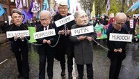 Pemrotes mengenakan topeng para tokoh dunia, di Glasgow (6/11/2021).  (Danny Lawson/PA via AP)