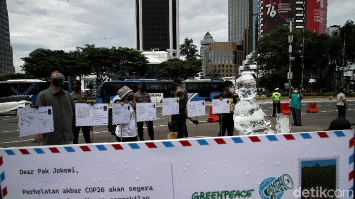 Aktivis Greenpeace menggelar aksi damai di Patung Kuda, Jakarta Pusat. Dalam aksi 1000 kartu pos dari rakyat untuk Jokowi itu, Greenpeace juga menghadirkan patung es.