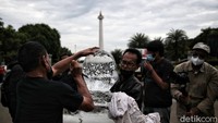Sejumlah aktivis membuat patung dari es di sela-sela aksi di Patung Kuda.