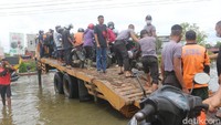 Polri dan BPBD menyiapkan truk tronton untuk membantu masyarkat menyeberangi genangan air. Warga dengan kendaraan mobil atau motor digratiskan menggunakan jasa tersebut. (Adi Saputro/detikcom)