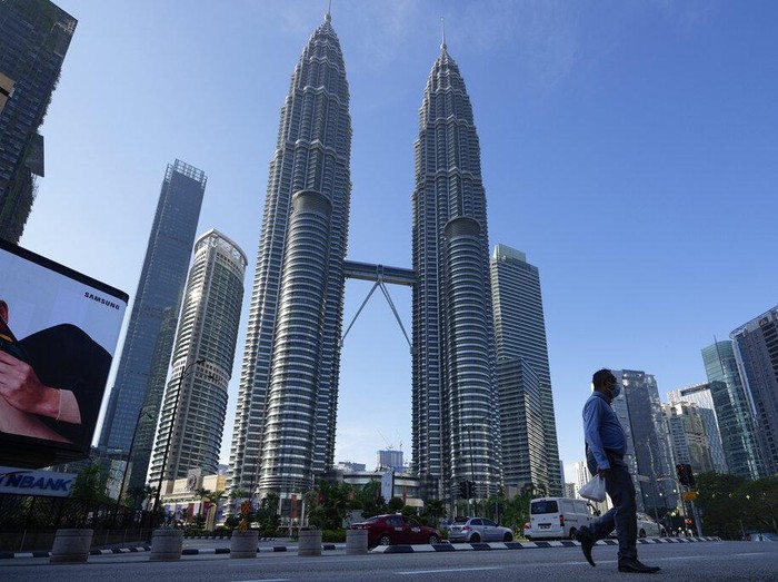 A man wearing a face mask walks along an empty road in front of the Twin Towers during the first day of Full Movement Control Order (MCO) in Kuala Lumpur, Malaysia, Tuesday, June 1, 2021. Malls and most businesses in Malaysia shuttered Tuesday as the country began its second near total coronavirus lockdown to tackle a worsening pandemic that has put its healthcare system on the verge of collapse. (AP Photo/Vincent Thian)