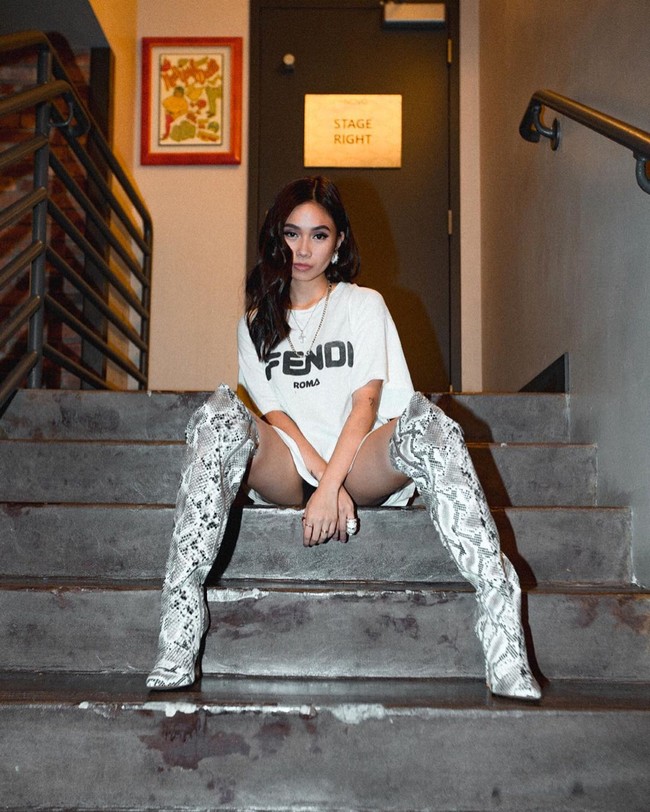 Mengenakan atasan oversized yang sederhana, penampilannya jadi maksimal dengan knee high boots bermotif kulit ular. Foto: Instagram @nikizefanya