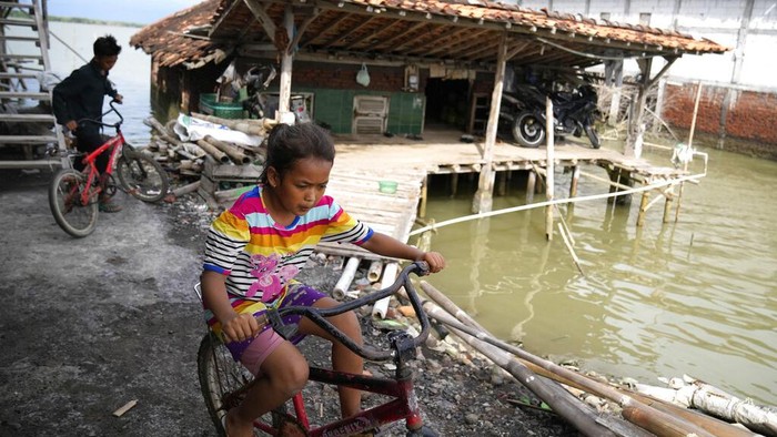 Children play near a house engulfed by sea water due to the rising sea levels in Bedono village, Central Java, Indonesia, Monday, Nov. 8, 2021. World leaders are gathered in Scotland at a United Nations climate summit, known as COP26, to push nations to ratchet up their efforts to curb climate change. Experts say the amount of energy unleashed by planetary warming would melt much of the planets ice, raise global sea levels and greatly increase the likelihood and extreme weather events. (AP Photo/Dita Alangkara)